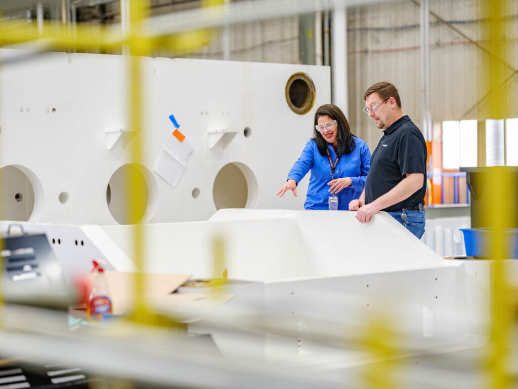 A platen for an injection molding machine on the left and two engineers developing process solutions in the middle background.